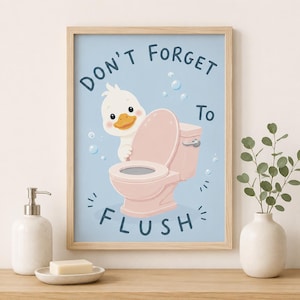 May include: A framed wall art print featuring a light blue background with a cartoon white duck peeking from behind a pink toilet. The text reads DON'T FORGET TO FLUSH in dark blue letters. Bubbles are scattered around the duck and toilet.