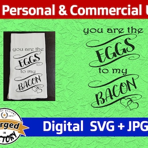 Puede incluir: Una toalla de cocina blanca con texto negro que dice "You are the eggs to my bacon" con dos pequeños corazones en la parte inferior. La toalla está sobre un fondo verde con un logotipo de Victory Designs.
