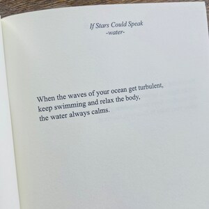 以下が含まれることがあります： 「If Stars Could Speak」と「-water-」のタイトルが書かれた開いた本のページ。困難な時に落ち着きを見つけることについての詩が、読みやすいフォントで印刷されています。