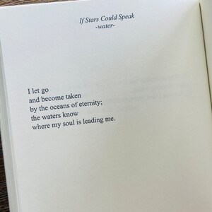 以下が含まれることがあります： 「If Stars Could Speak -water-」というタイトルの詩が書かれた開いた本。詩はページの中央に配置され、最初の行は「I let go」です。紙はオフホワイトで、テキストはシンプルで読みやすいフォントです。
