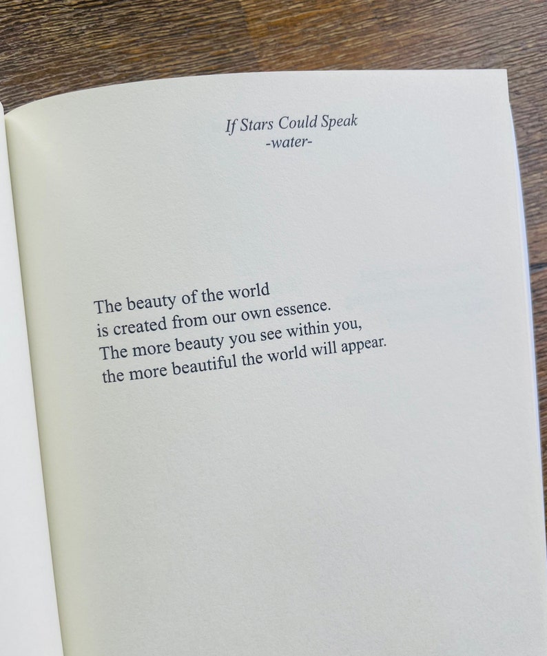 以下が含まれることがあります： クリーム色のページにテキストが書かれた開いた本。タイトル「If Stars Could Speak」とサブタイトル「-water-」が上部にあります。下のテキストは「世界の美しさは私たち自身の本質から生まれます。あなた自身の中に美しさを見れば見るほど、世界はより美しく現れます。」と書かれています。