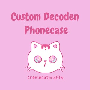 May include: Pink background with the text "Custom Decoden Phonecase" in pink. A white cat face with pink and blue eyes and a pink stripe on its head is centered below the text. The text "cremecatcrafts" is at the bottom.