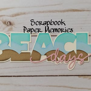 May include: Scrapbook Paper Memories title with the words "Beach Days" in turquoise blue, white, and brown with a pink swirl.