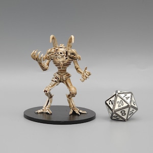 May include: A detailed skeletal figure with horns and claws, painted in a bone white colour, stands on a black circular base. A 20-sided die is in the background.