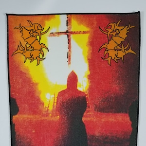Op de afbeelding: Een zwart-witte patch met een rode en oranje achtergrond. De patch toont een silhouet van een persoon die voor een kruis staat met vlammen erachter. De tekst "CHAOS A.D." is op de patch gedrukt.