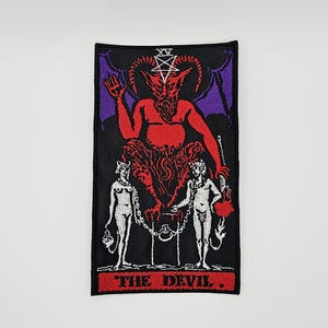May include: A rectangular embroidered patch featuring a red devil figure with horns and a pentagram above its head, flanked by two chained figures. The background is black with purple accents, and the text THE DEVIL is stitched in red at the bottom.