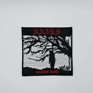 Könnte beinhalten: Schwarzer quadratischer Aufnäher mit dem Wort "NAILS" in roter gotischer Schrift oben. Darunter eine schwarz-weiße Illustration einer Silhouette unter einem Baum. Die Worte "unsilent death" stehen unten in Rot.