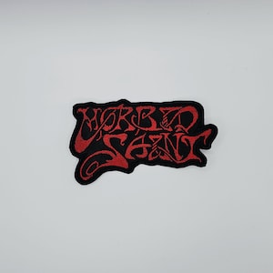 May include: Black embroidered patch with the words "MORBID SEEN" in red, stylized lettering. The patch has a black border and is likely for clothing or accessories.