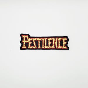 May include: A rectangular patch with the word "PESTILENCE" embroidered in yellow and red on a black background. The patch has a jagged edge design and is likely for clothing or accessories.