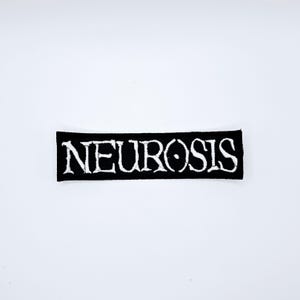 Może przedstawiać: Czarna prostokątna naszywka z białym napisem "NEUROSIS". Naszywka jest umieszczona na białym tle.
