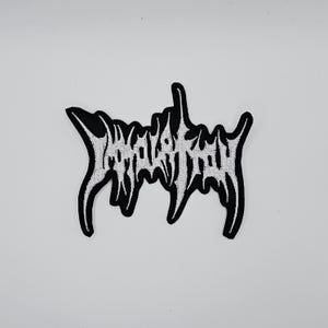 Op de afbeelding: Zwart en wit geborduurde patch met gestileerde tekst. De patch heeft een zwarte rand en de tekst is wit. Het ontwerp is in gotische stijl, geschikt voor jassen, tassen of andere stoffen items.