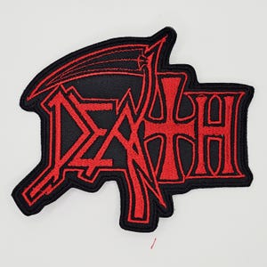 May include: Embroidered patch in black and red, featuring the word "DEATH" in a stylized font with a scythe design. The patch has a black background with red stitching and a black border.