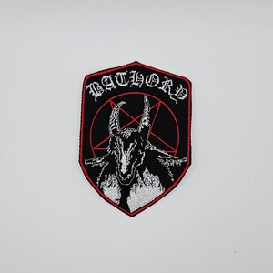 May include: Embroidered patch featuring the word "BATHORD" in white gothic lettering above a black goat head with a red pentagram on a black background. The patch has a red border and a shield shape.