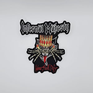 Puede incluir: Parche bordado negro con las palabras "Infernal Majesty" en blanco, sobre una calavera con corona. El parche también presenta las palabras "None Shall Defy" en rojo. Un accesorio único.