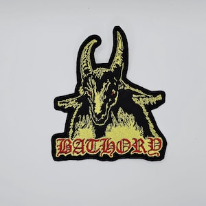 May include: Embroidered patch featuring a black goat head with yellow details and red eyes. The word "BATHORY" is embroidered in red gothic lettering below the goat's head. The patch has a black border.