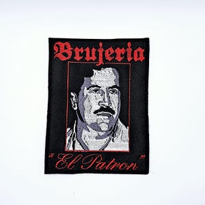 May include: Black embroidered patch with a portrait of a man with a moustache, framed in red. The words "Brujeria" and "El Patron" are embroidered in red script. The patch is rectangular in shape.