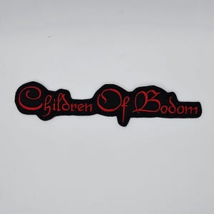 Könnte beinhalten: Ein schwarzer, gestickter Aufnäher mit dem Schriftzug "Children Of Bodom" in roter Schrift. Der Aufnäher hat eine längliche, geschwungene Form und ist für Kleidung gedacht.