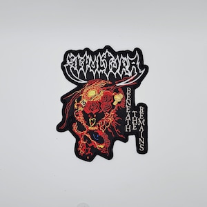Könnte beinhalten: Gestickter Aufnäher mit einem Totenkopf-Design, roten Rosen und dem Text "STRANGULATE" oben und "BENEATH THE REMAINS" vertikal rechts. Der Aufnäher hat einen schwarzen Rand und befindet sich auf weißem Hintergrund.