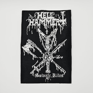 Op de afbeelding: Een rechthoekige zwarte stoffen patch met wit geborduurde afbeeldingen en tekst. De bovenste tekst luidt HELLHAMMER, terwijl de onderste tekst Satanic Rites luidt. Het centrale ontwerp toont een gestileerde bijl en zwaard die elkaar kruisen.