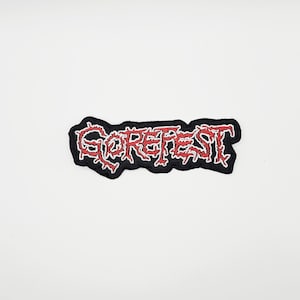 Peut inclure: Un écusson brodé noir avec le mot "GOREFEST" en lettrage rouge stylisé. L'écusson a une bordure blanche et est posé sur un fond blanc. Le design est audacieux et accrocheur.