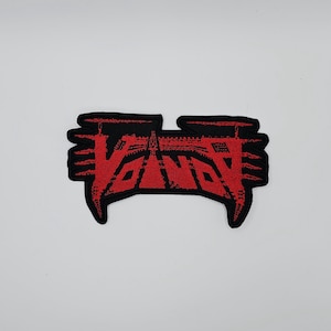 May include: A black and red embroidered patch with the word "VANDY" in a stylized font. The patch has a unique shape with pointed edges and a textured appearance, suitable for sewing onto clothing or accessories.