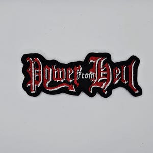 Könnte beinhalten: Schwarzer, gestickter Aufnäher mit dem Schriftzug "Power from Hell" in gotischer Schrift. Der Text ist weiß mit roter Umrandung. Der Aufnäher hat einen schwarzen Hintergrund und eine unregelmäßige Form.