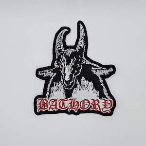 Könnte beinhalten: Gestickter Aufnäher mit einem schwarzen Ziegenkopf mit roten Augen und weißen Details. Das Wort "BATHORD" ist in roten gotischen Buchstaben gestickt. Der Aufnäher ist für Kleidung oder Accessoires gedacht.