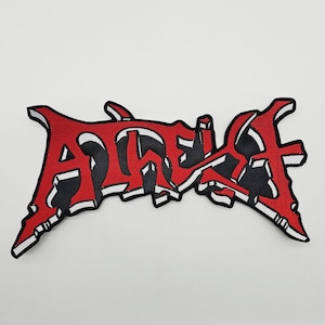 May include: A red and black embroidered patch with the word "ADEPT" in a stylized, gothic font. The patch has a white border and is likely designed to be ironed or sewn onto clothing or accessories.