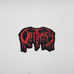 Może przedstawiać: Czarna, haftowana naszywka z napisem "OBITUARY" w czerwonych, ociekających literach. Naszywka ma nieregularny kształt. Tekst jest w gotyckiej czcionce, co nadaje jej estetykę heavy metalu.