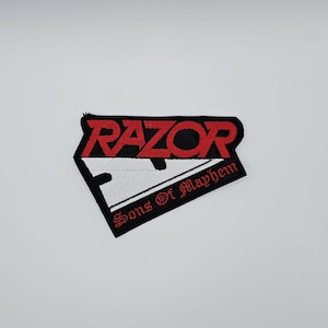 May include: A black and white patch with the word "RAZOR" in red, arched across the top. Below, a white slash divides the patch, and the words "Sons Of Mayhem" are written in red along the bottom edge.
