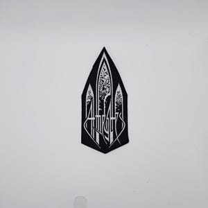 May include: Black and white embroidered patch with a pointed top. The patch features stylized white text and decorative elements within a black, elongated, shield-like shape. The design has a gothic or medieval aesthetic.