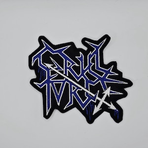 May include: Black embroidered patch with the text "BRUTAL FORCE" in blue and white. The patch has a jagged, irregular shape and features a white arrow design. The text is stylized with sharp, angular lines.