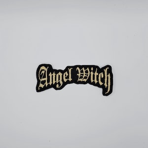 Könnte beinhalten: Schwarzer, gestickter Aufnäher mit den Worten "Angel Witch" in goldfarbenen gotischen Buchstaben. Der Aufnäher hat einen schwarzen Rand und ist zum Aufnähen oder Aufbügeln auf Kleidung oder Accessoires gedacht.