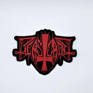 Op de afbeelding: Geborduurde patch met het woord "BEASTCRAFT" in rode gotische letters. De patch heeft een zwarte rand en een centraal omgekeerd kruisontwerp, met extra kruisdetails. Geschikt voor kleding of accessoires.