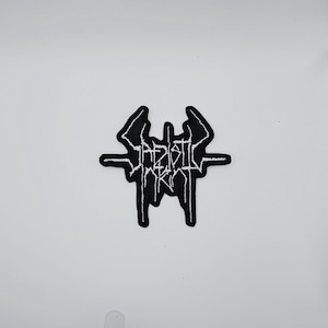 May include: Black and white embroidered patch with the text "SADISTIC ERA" in a gothic font. The patch has a unique, stylized design with sharp edges and a symmetrical layout. The patch is likely for clothing or accessories.