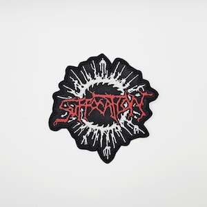 Può includere: Toppa nera ricamata con la scritta "SUFFOCATION" in rosso, con lettering stilizzato. La toppa ha uno sfondo nero con un bordo bianco e appuntito, che ricorda un'esplosione. Per abbigliamento o accessori.
