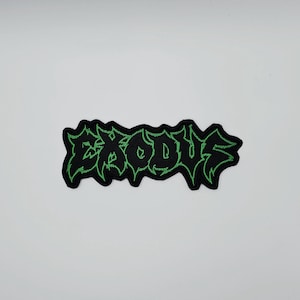 Op de afbeelding: Zwart geborduurd embleem met het woord "EXODUS" in groene, gestileerde letters. Het embleem heeft een decoratieve, gekartelde rand. Geschikt voor jassen, tassen of andere kledingstukken.