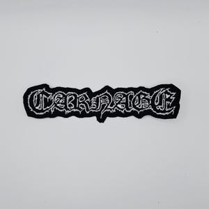 Op de afbeelding: Zwart en wit geborduurde patch met het woord "CORRUPTED" in een gestileerd, gotisch lettertype. De patch heeft een zwarte rand en is ontworpen om op kleding of accessoires te worden genaaid.