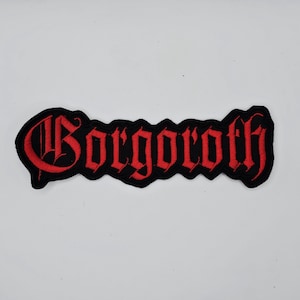 May include: Embroidered patch featuring the word "Gorgoroth" in red gothic script on a black base. The patch has a black border, suitable for application on clothing or accessories.