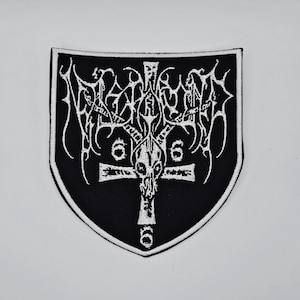 May include: Black and white embroidered patch in a shield shape. The patch features a gothic design with a cross, skull, and the number six. The border is white, and the background is black. Suitable for clothing or accessories.