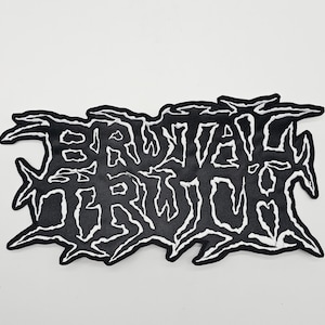 May include: A black and white patch featuring the words "BRUTAL TRUTH" in a jagged, stylized font. The patch has a black background with white stitching outlining the text and the irregular border.