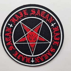 May include: A black and white circular patch with a red pentagram and a red goat's head inside. The text "Hail Satan" is written in red around the edge of the patch.