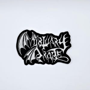 May include: Black embroidered patch with the words "MIRIARY SHAPE" in a gothic font. The patch features a bat wing design on the left side, with white thread on a black background.