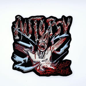 May include: Black patch featuring the word "AUTOSY" in red, dripping lettering. A screaming figure with red and white details is in the centre. The text "SEVERED SURVIVAL" is at the bottom. The patch has a black border.