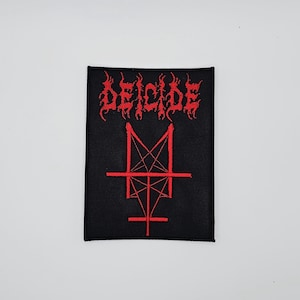 May include: Black rectangular patch with the word "DEICIDE" in red, stylized, gothic lettering above a red inverted cross and pentagram design. The patch is likely for a jacket or bag, and is a symbol of the death metal band.