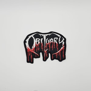 May include: Black patch featuring the word "Obituary" in white, stylized lettering. Red drips cascade from the bottom, creating a dripping effect. The patch has an irregular, unique shape.