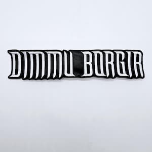 Puede incluir: Parche bordado en blanco y negro con el texto "DIMMU BORGIR" en una fuente estilizada. El texto está contorneado en blanco sobre un fondo negro. El parche es rectangular y tiene una forma ligeramente curvada.