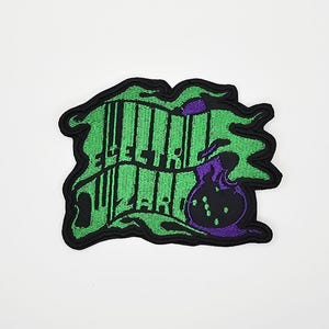 Könnte beinhalten: Gestickter Aufnäher mit dem Schriftzug "ELECTRIC WIZARD" in Grün, mit schwarzem Rand. Das Design beinhaltet eine lila Zaubertrankflasche. Der Hintergrund ist grün mit schwarzer Umrandung, ideal für Kleidung oder Accessoires.