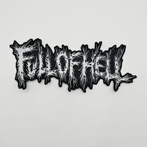 May include: A black fabric patch featuring the white embroidered text Full of Hell in a jagged, spiky, and distorted font style. The lettering has a rough, weathered appearance with thin, sharp lines extending from the characters, creating a chaotic and textured visual effect across the entire design.