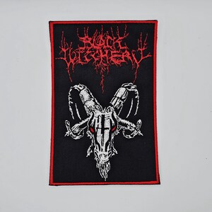 Puede incluir: Parche rectangular negro con borde rojo. Presenta el texto rojo "Blood Vulturey" sobre una ilustración blanca de una calavera de cabra con ojos rojos. La letra y la calavera son detalladas.